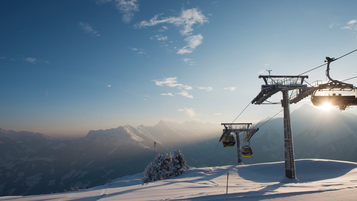 Skifahren und Seilbahnfahrten im größten Skigebiet Österreichs – Winterpanorama in den Alpen Seilbahn mit Blick auf schneebedeckte Berge im größten Skigebiet Österreichs bei Sonnenuntergang.
