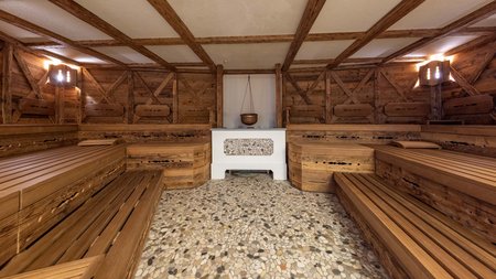 Traditionelle Sauna im Wellnessbereich – Entspannung und Regeneration in der Hitze Holzsauna mit traditionellen Holzbänken und zentralem Ofen für ein authentisches Saunaerlebnis.