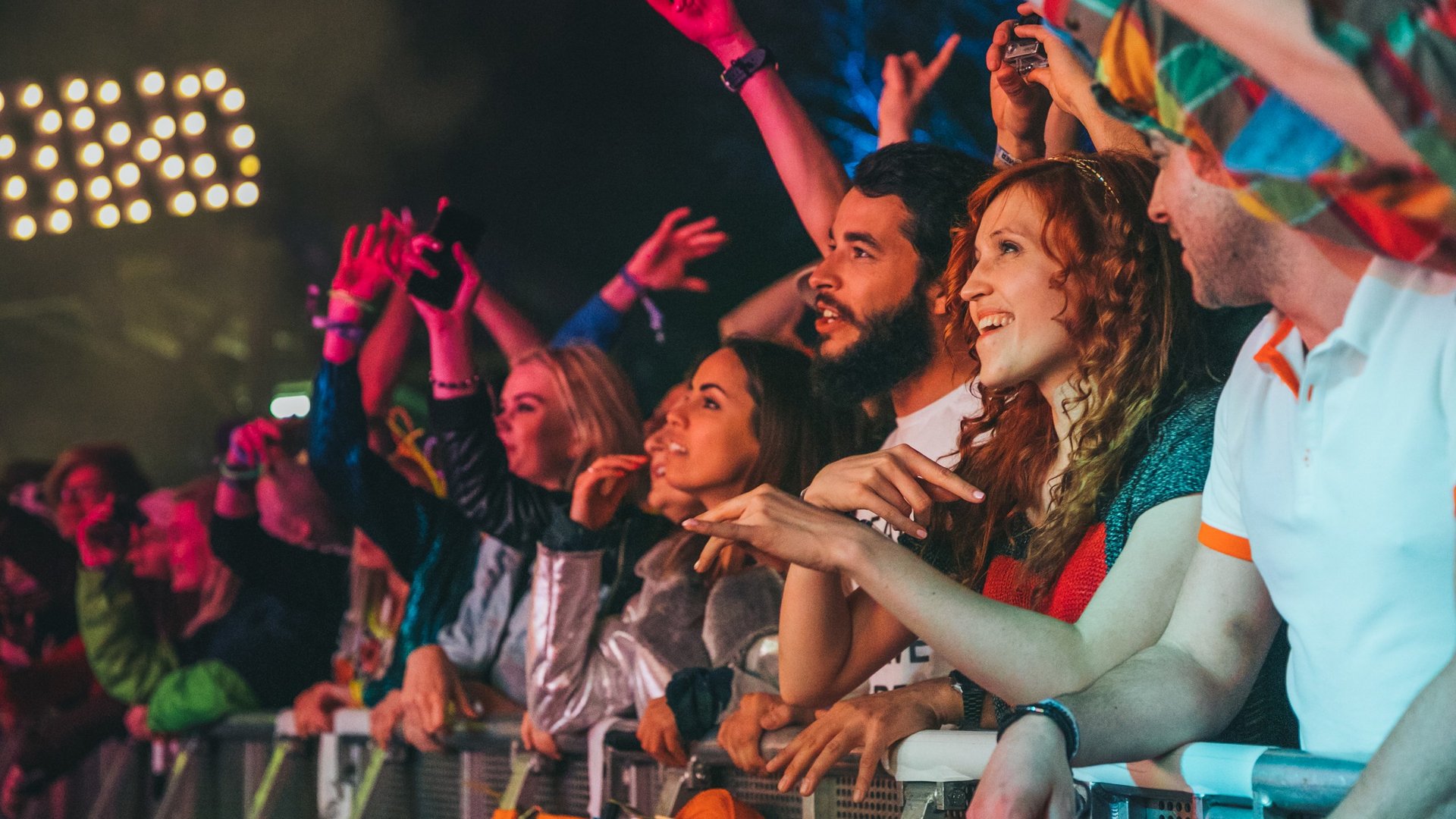 Konzertspaß in der ersten Reihe Menschen in der ersten Reihe eines Konzerts genießen die Show, lächelnd und voller Energie.